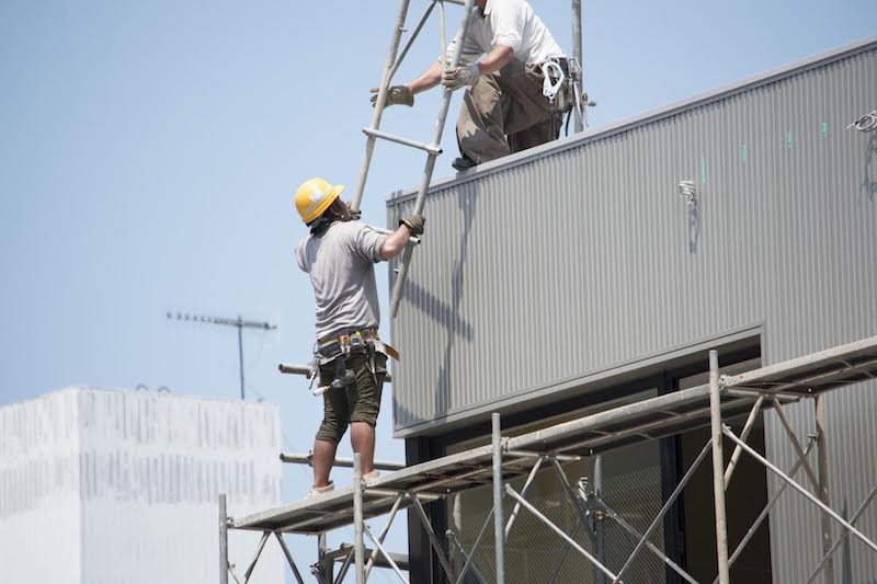 足場の鉄鋼を渡す男性